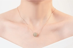 Gros plan d'un collier pendentif sphérique en or rose serti de cristaux blancs brillants