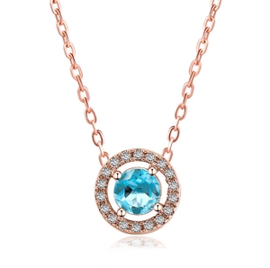 Detailed macro of a rose gold circular pendant with a centered blue zircon and halo diamonds