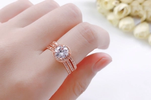 Detailopname van driedelige roségouden trouwringset met zirkonia stenen aan de hand