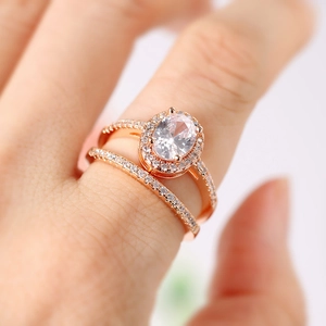 Close-up of a rose gold bridal ring set with oval-cut cubic zirconia on a female hand
