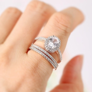 Detailed close-up of a 3-piece engagement ring set with oval center stone on woman's hand