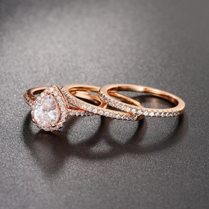 Dettaglio del set di tre anelli da sposa in oro rosa con pietra a pera e pavé di zirconi