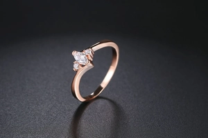 Macro shot of rose gold marquise zircon ring featuring three stones on dark background