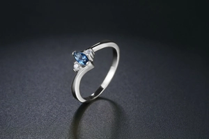 Macro detail of marquise-cut navy blue stone ring with side zircon accents on silver band