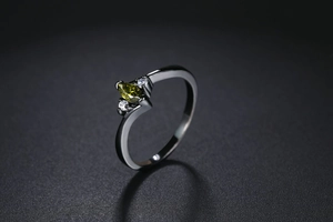 Macro shot of marquise-cut olive green gemstone ring with side stones on black band