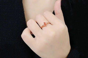 Close-up of a rose gold ring featuring a marquise red gemstone and side diamonds