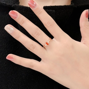 Rose gold marquise-cut red stone ring with side zircon accents worn by a model