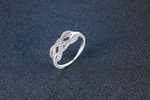 Macro shot of silver infinity ring with sparkling pavé zircons on dark background