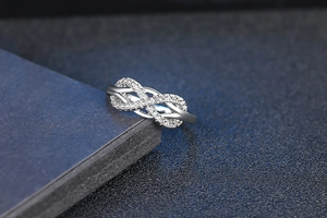 Detailed view of infinity knot ring with micro-set zircons on dark textured base