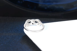 Macro shot of silver bow knot ring with cubic zirconia on a blue background