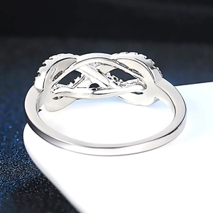 Silver infinity bow ring with sparkling cubic zirconia on a minimalist white stand