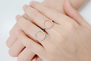 Close-up of silver and rose gold O-shaped rings with zircon pavé setting on hand