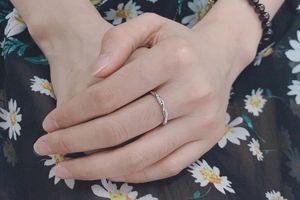 Primer plano de un anillo de compromiso plateado trenzado con circonitas en la mano
