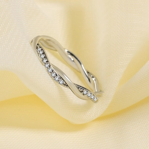 Elegante anillo de plata trenzada con micropavé de circonitas sobre fondo seda