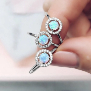 Elegant opal rings with sparkling halo diamonds in a silver finish on fingers
