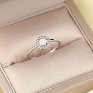 Classic silver-plated opal ring with shimmering halo of zircon on elegant silk cushion