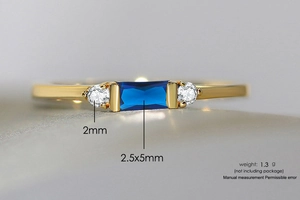 Macro detail of a 14K gold ring featuring a rectangular blue gem and side zircons