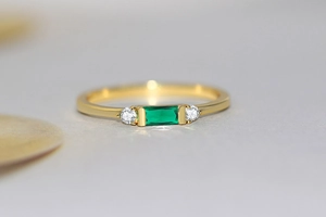 Macro view of emerald-cut green gemstone on a classic 14K gold-plated geometric ring