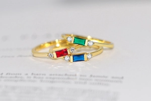 Macro shot of three stacked 14K gold rings with rectangle red blue green zircon stones