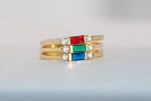 Macro detail of three 14K gold plated rings with emerald cut red, green and blue stones