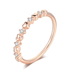 Macro detail of slim rose gold ring with heart patterns and sparkling zircon stones