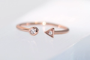 Macro detail of geometric rose gold ring with inlaid circular and triangular zircon stones
