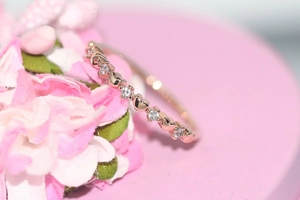 Macro shot of rose gold heart-shaped ring band with sparkling zircon stones