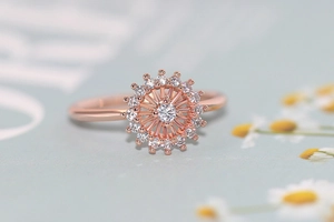 Primer plano de anillo de flor en oro rosa con piedra central y detalles brillantes