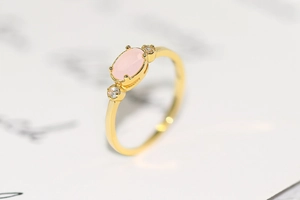 Close-up of 14k gold-plated ring featuring an oval pink gemstone and small zircon accents