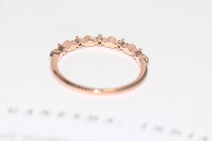 Macro view of slender rose gold ring with prong-set zircon stones and polished finish