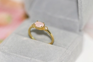Detail of 14k gold-plated ring featuring pink oval gemstone and sparkling zircon accents