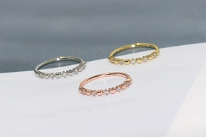 Detail of three slim rings in gold, silver, and rose gold with heart zircon inlay
