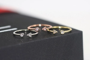 Macro detail of geometric open rings in silver, gold and rose gold with zircon stones