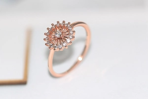 Primer plano macro de anillo de flor en oro rosa con circonitas sobre fondo blanco