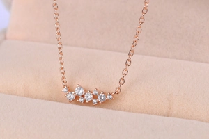 Macro-opname van roségouden ketting met een onregelmatige zirkooncluster op beige fluweel