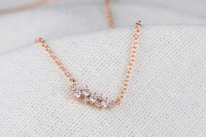 Macro-opname van roségouden sterrenbeeldketting met witte zirkonia-cluster hanger
