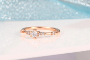 Close-up of rose gold ring with 7 sparkling diamonds on a blue glitter background