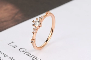 Close-up of rose gold ring with seven sparkling round diamonds in a claw setting