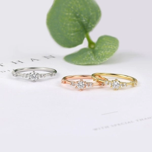 Three minimalist rings in gold, silver and rose gold with tiny diamonds and green leaves