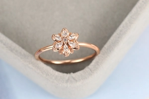 Macro shot of rose gold flower ring with marquise-cut crystals on a velvet box