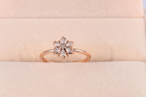 Detail of flower ring featuring marquise-cut zircon petals on a beige velvet surface