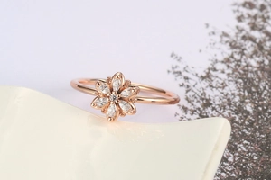 Macro shot of rose gold flower ring with marquise-cut zircon petals on ceramic tray