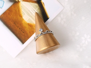Macro detail of silver crown ring with cubic zirconia on a vintage gold stand