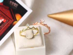 Detailed view of gold and rose gold crown rings with zircon stones and beaded edges