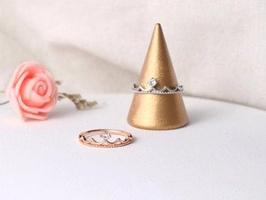 Detailed view of crown-shaped rings in rose gold and silver with zircon accents