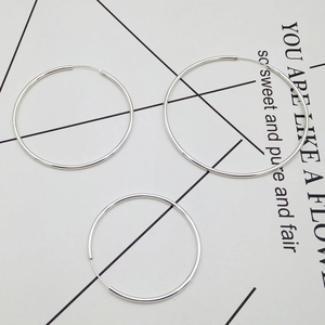 Detailed set of three polished silver hoop earrings in varying sizes on minimalist background