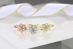 Detailed view of flower rings in rose gold, silver, and gold with marquise-cut zircon
