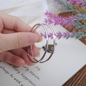 Polished silver hoop earrings held by hand showcasing large classic circular design