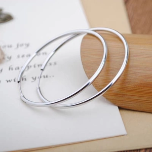 Detail shot of silver hoop earrings on a minimalist wooden and paper gift display
