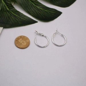Detail showing the size of silver hoop earrings next to a reference coin for scale